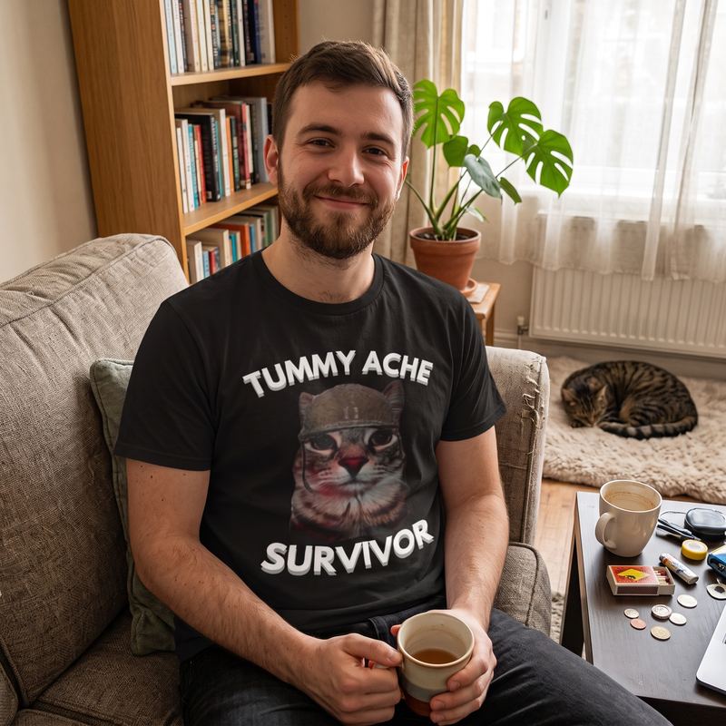 Someone on a sofa holding a mug, wearing the tummy ache survivor tee.